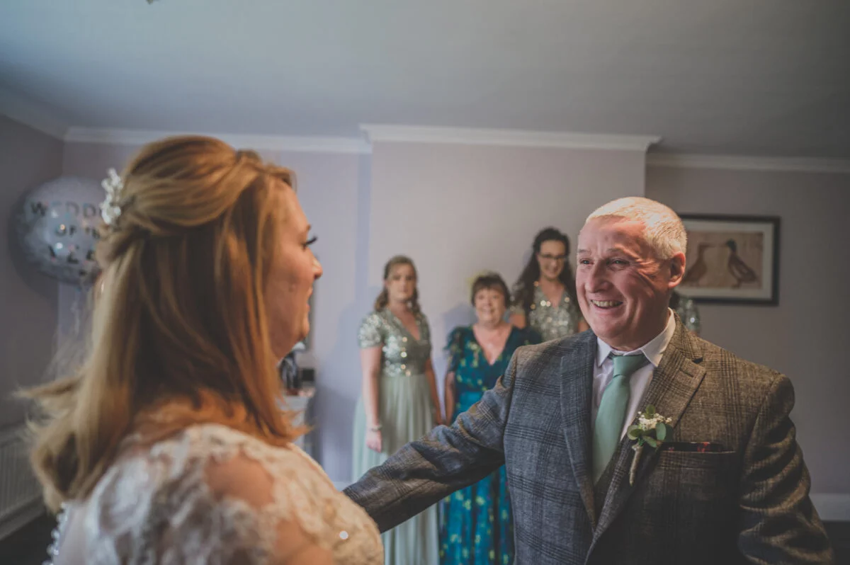 A man smiles as his bride walks down the aisle.