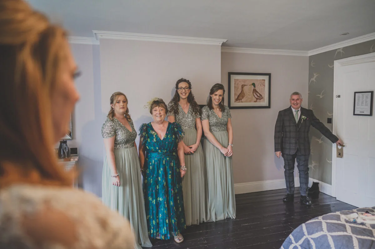 A bride and her bridesmaids are standing in front of a mirror.