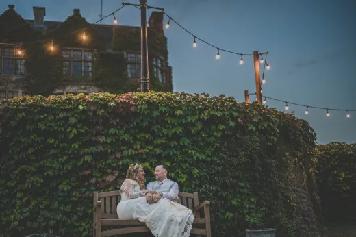 A bride and groom sitting on a bench in front of a castle.