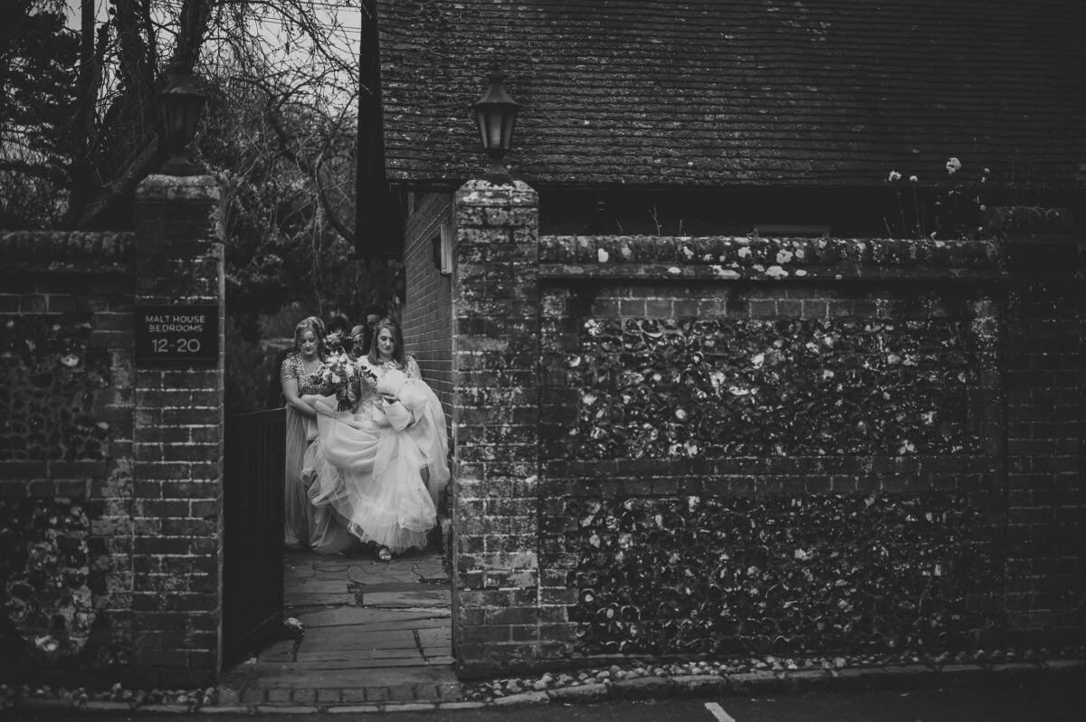 Black and white photo of bride and groom walking through a gate.