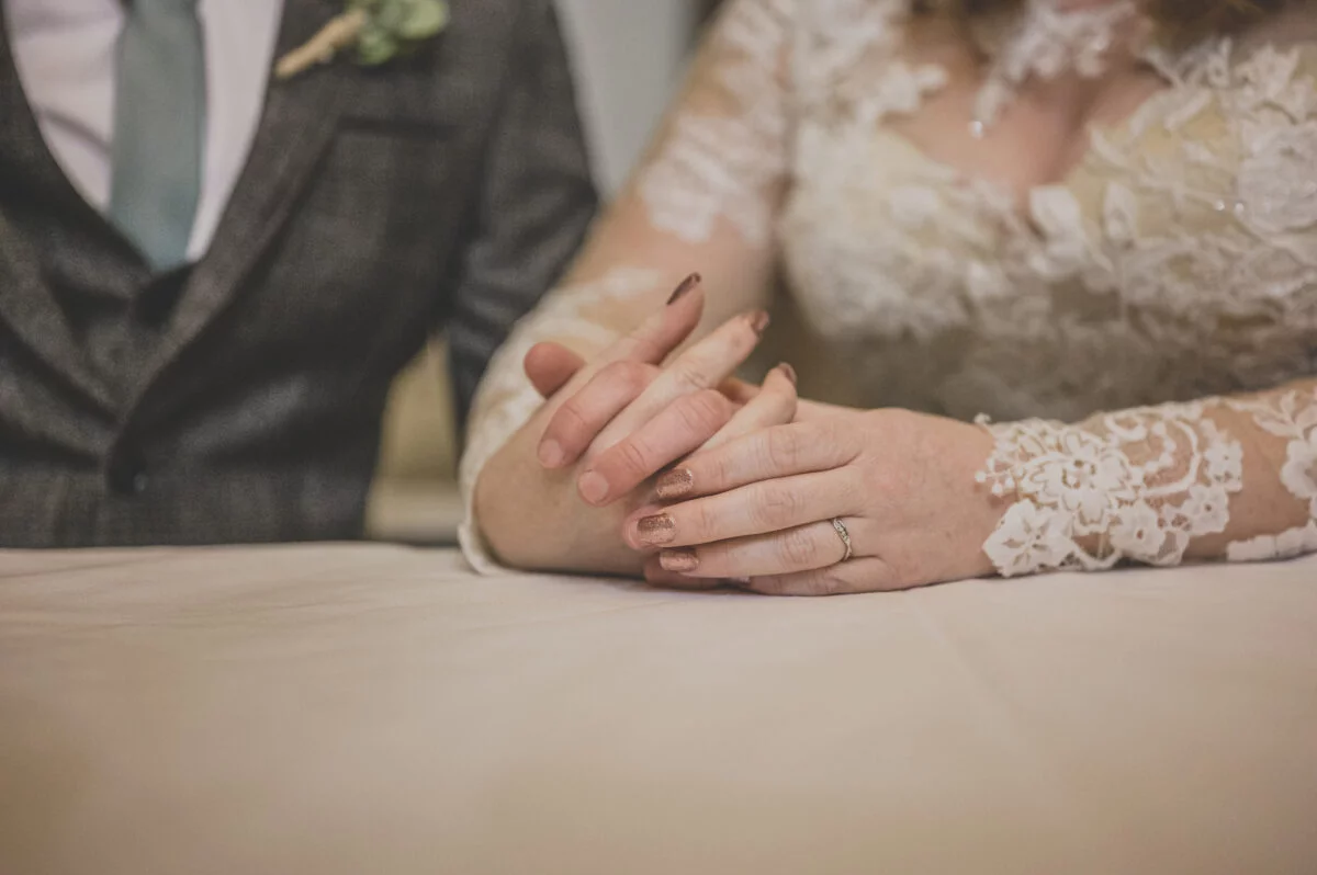 A bride and groom holding hands on a table.