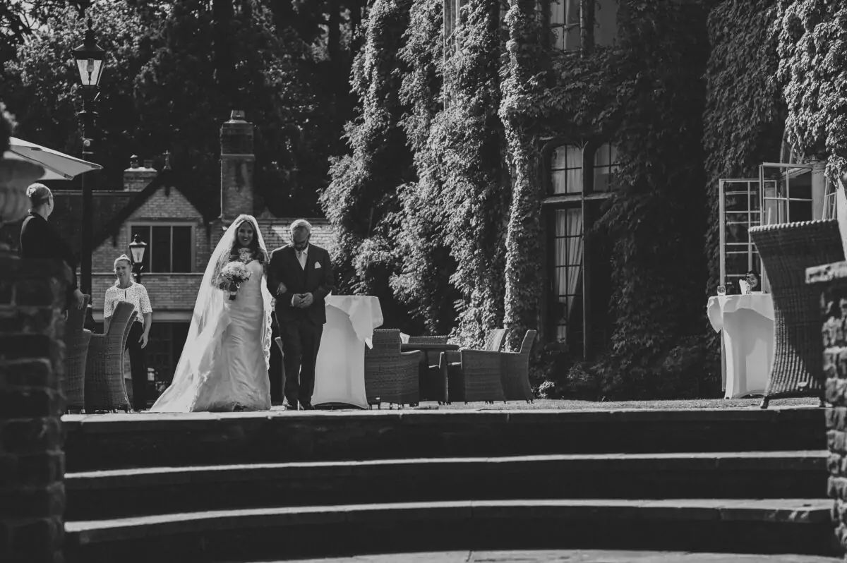 A black and white photo of a bride and groom walking down steps.