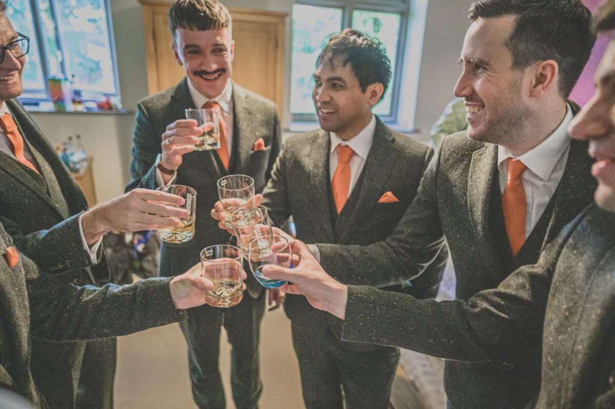 A group of groomsmen toasting glasses of whisky.