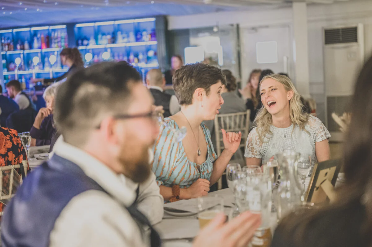 A group of people laughing at a wedding reception.