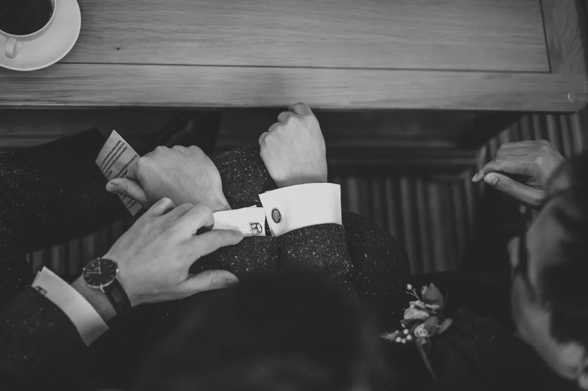 A black and white photo of a group of men with their hands on their wrists.
