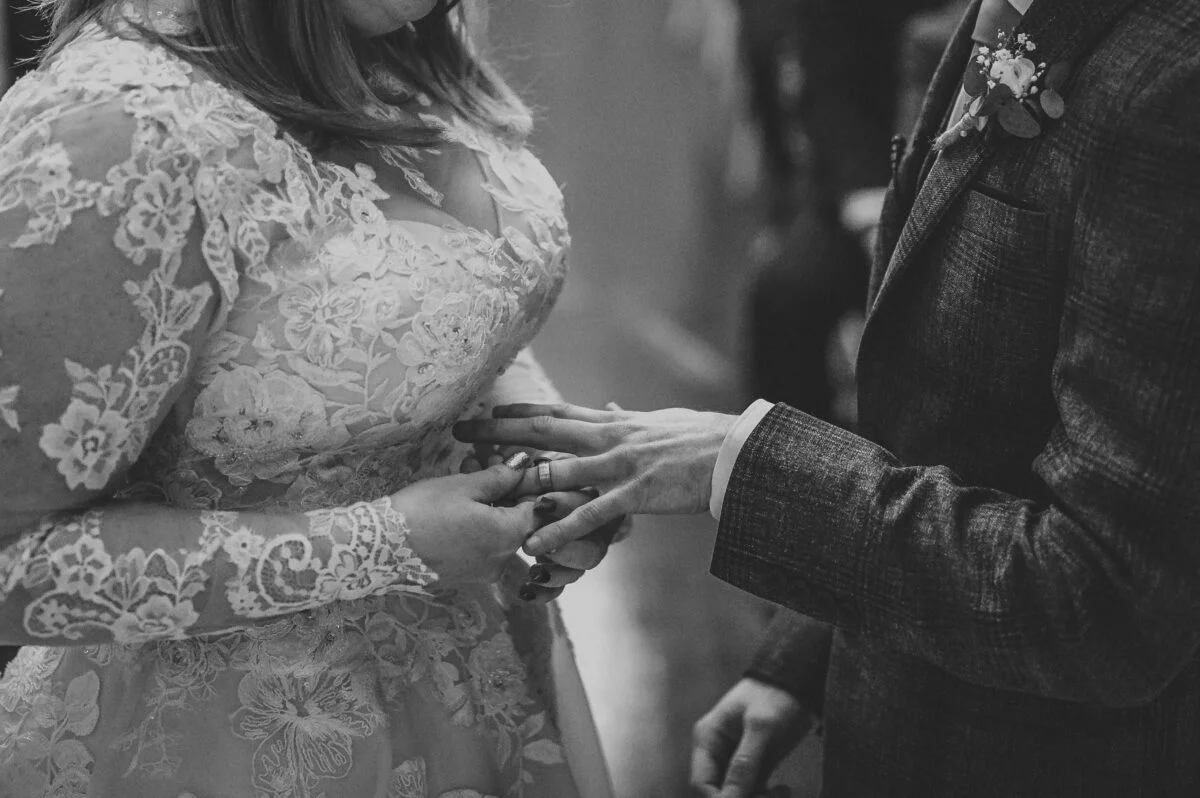 A bride is putting her ring on her husband's finger.
