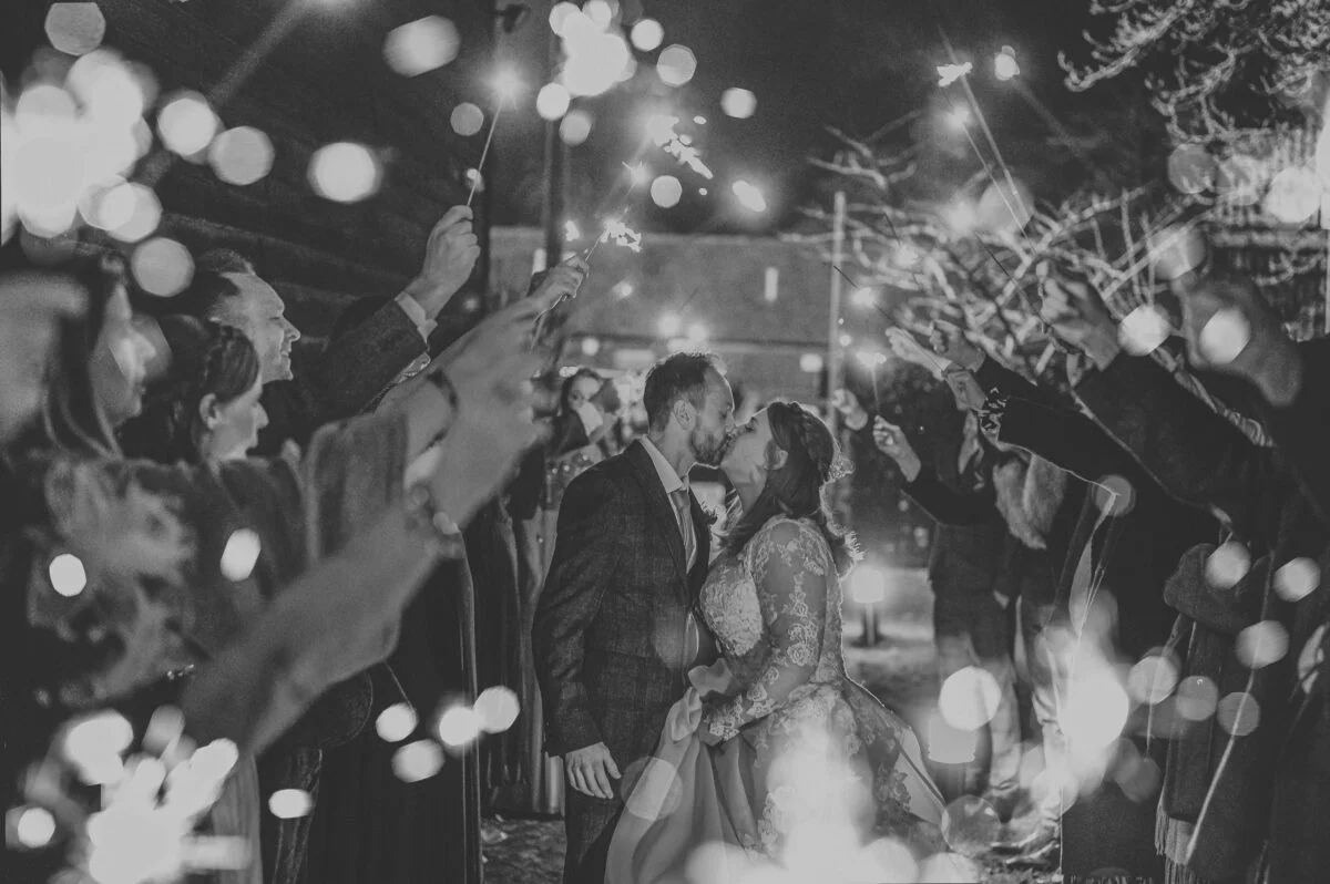 Black and white photo of bride and groom with sparklers.