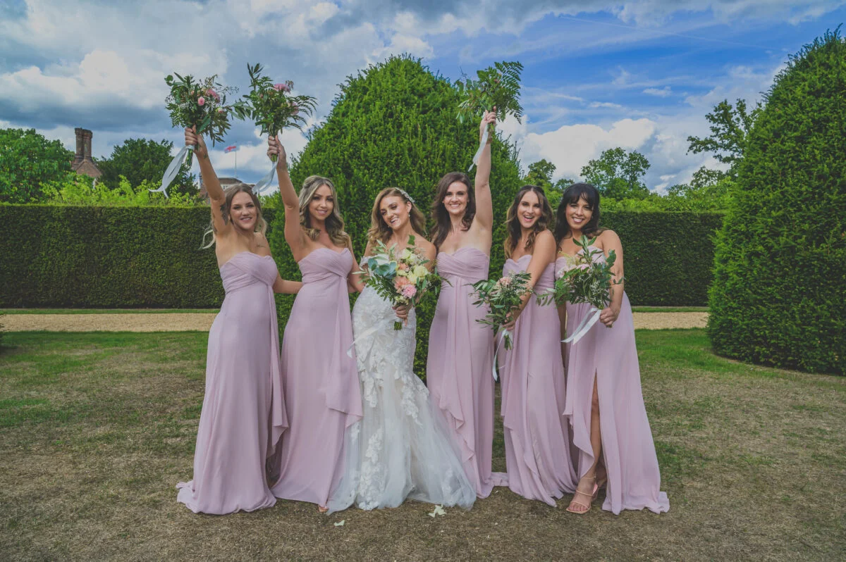 The bridesmaids are holding their bouquets in the air.