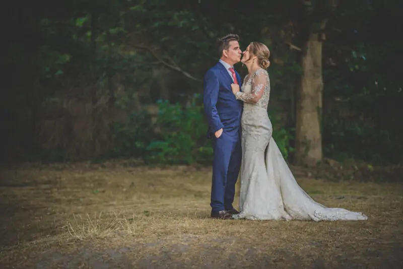 A bride and groom kissing in the woods.