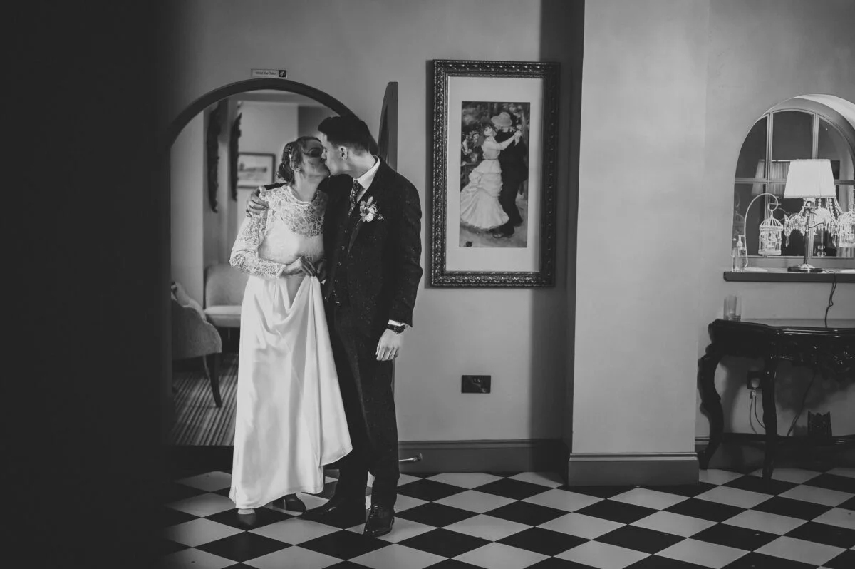 A bride and groom standing in front of a mirror.