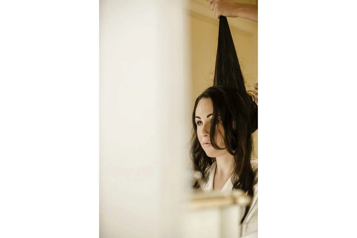 A woman getting her hair done in front of a mirror.