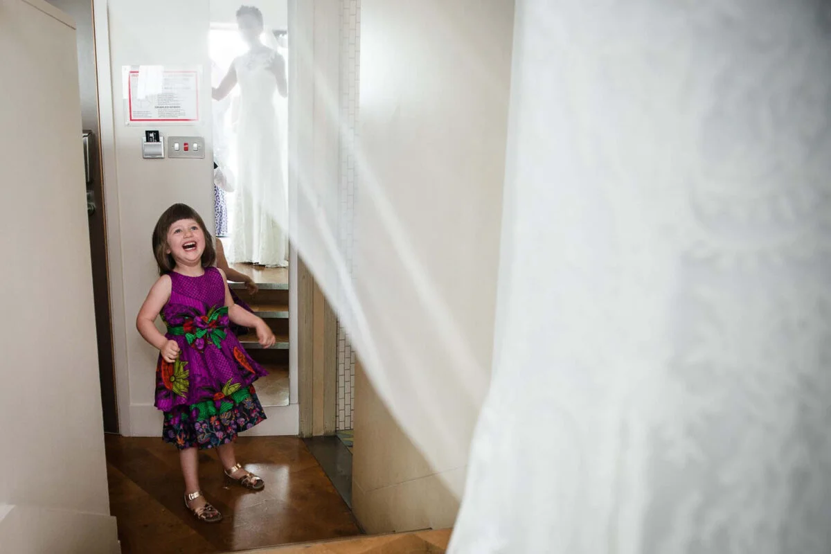 A little girl in a purple dress standing in a doorway.