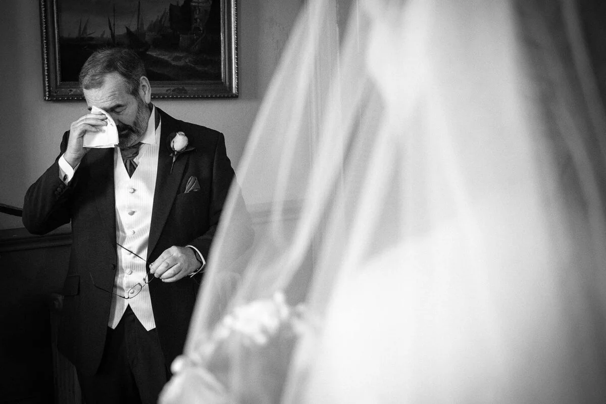 A man in a suit is wiping his face with a tissue.