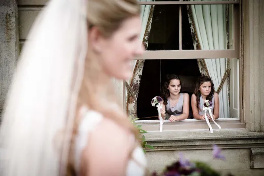 A bride and her bridesmaids look out of a window.