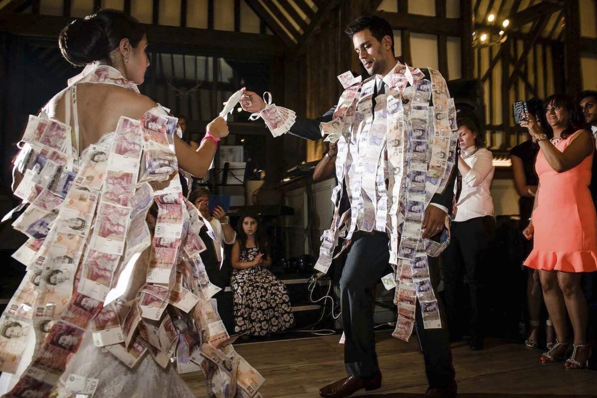 A bride and groom dancing on a stage covered in money.