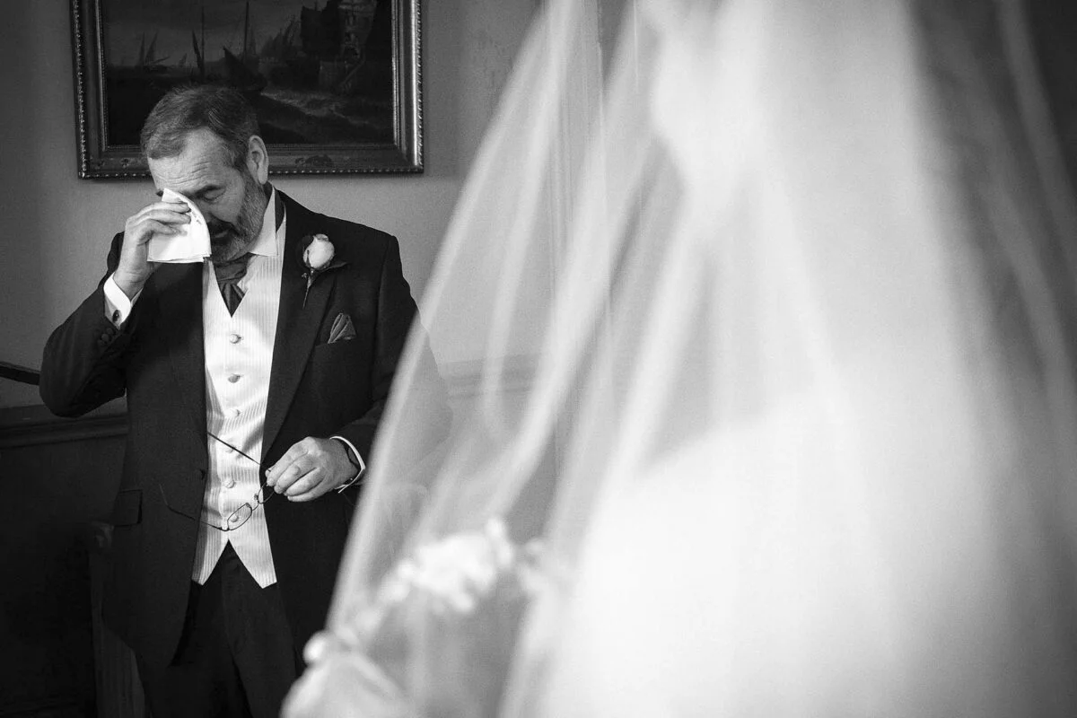 A man in a suit is wiping his face with a tissue.