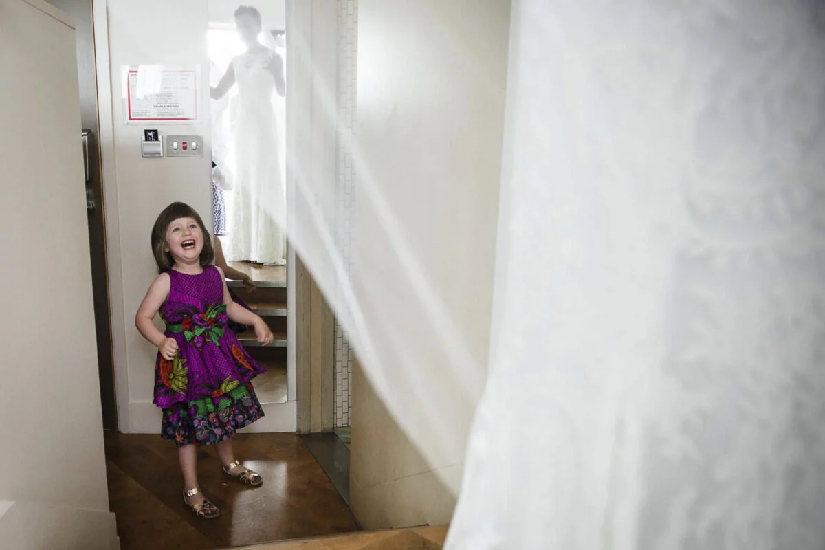 A little girl in a purple dress standing in a doorway.