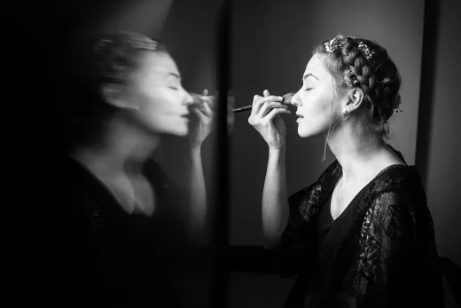 A woman is getting her makeup done in front of a mirror.
