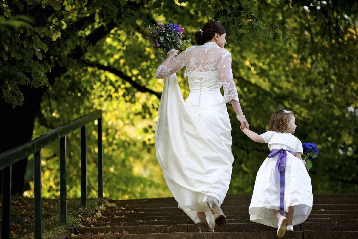 A bride and flower girl walking down a set of stairs.