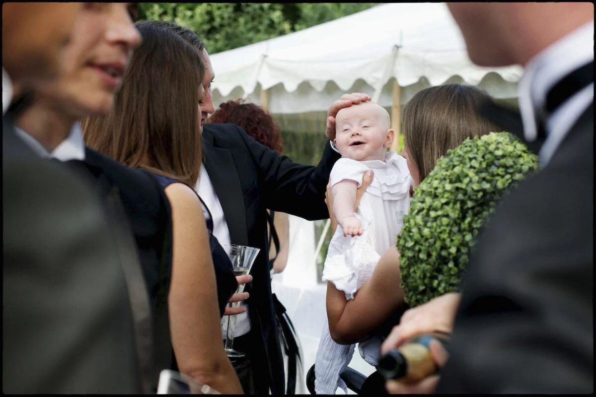 A baby is being held by a man in a tuxedo.