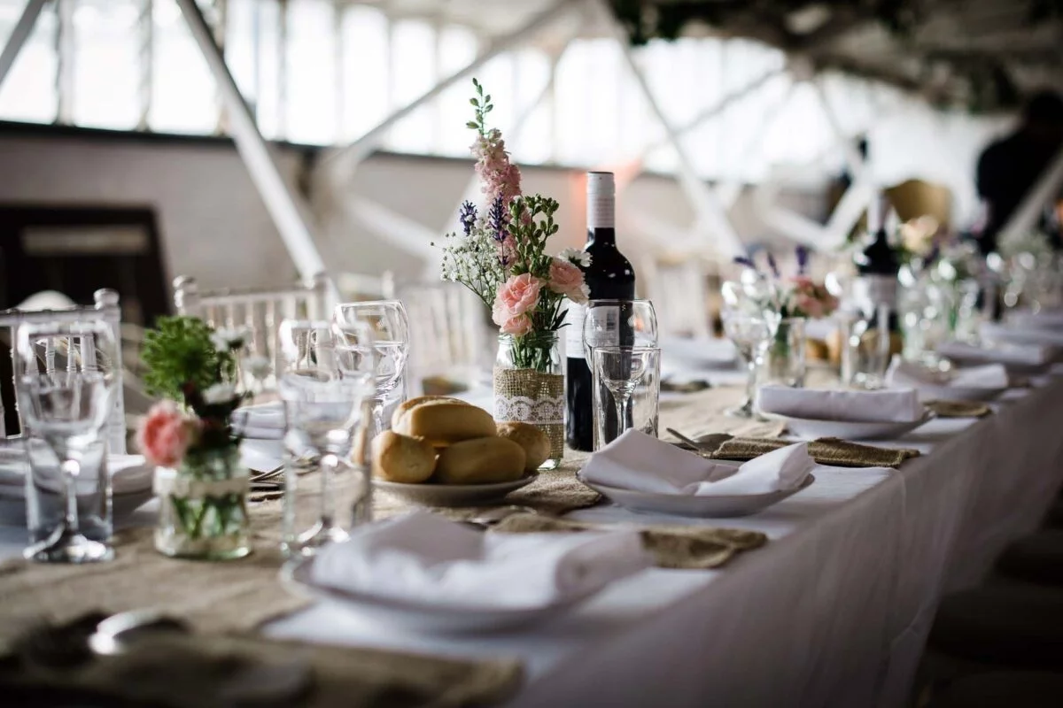 A long table set with wine glasses and flowers.