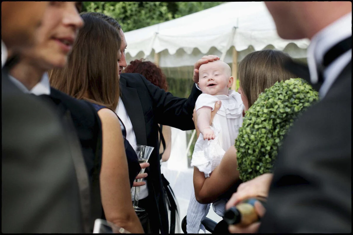 A baby is being held by a man in a tuxedo.