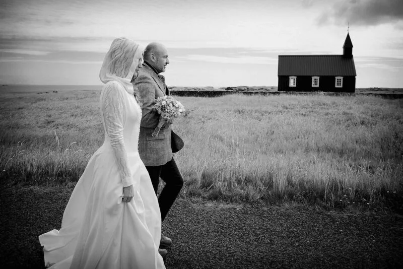A bride and groom walking in front of a church in iceland.