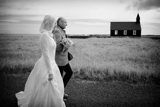 A bride and groom walking in front of a church in iceland.