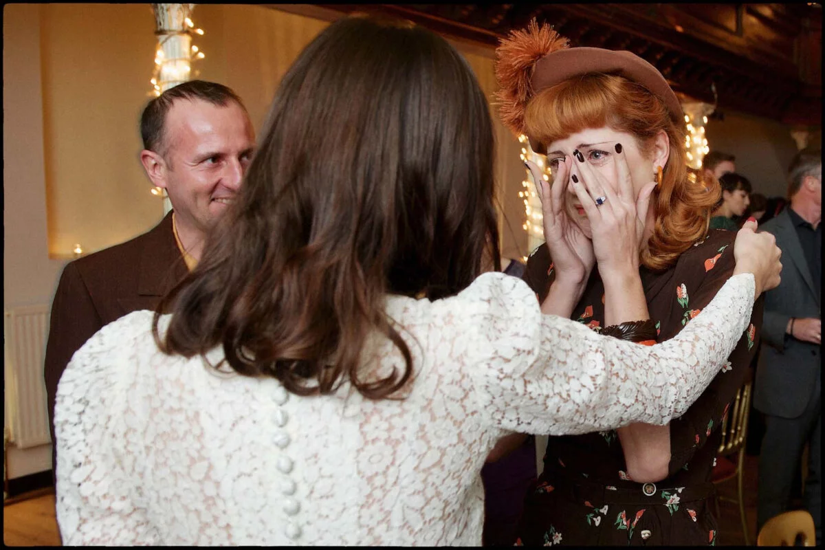 A woman wearing a hat is talking to a man at a party.