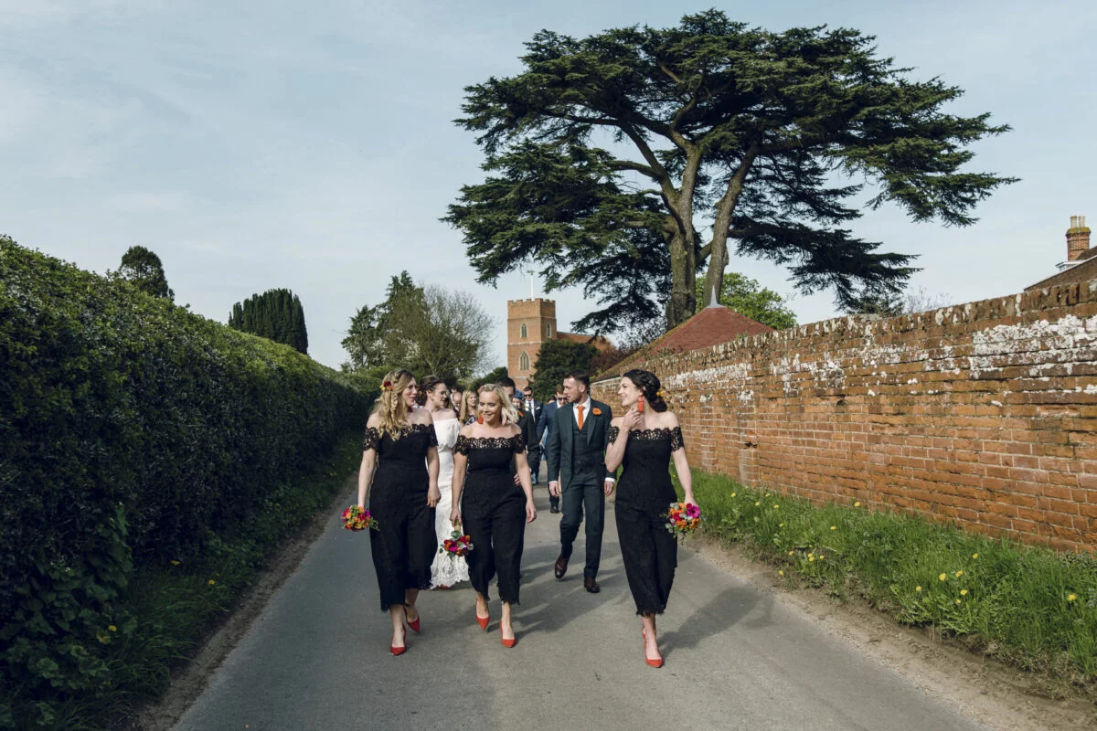 A group of bridesmaids walking down a road.