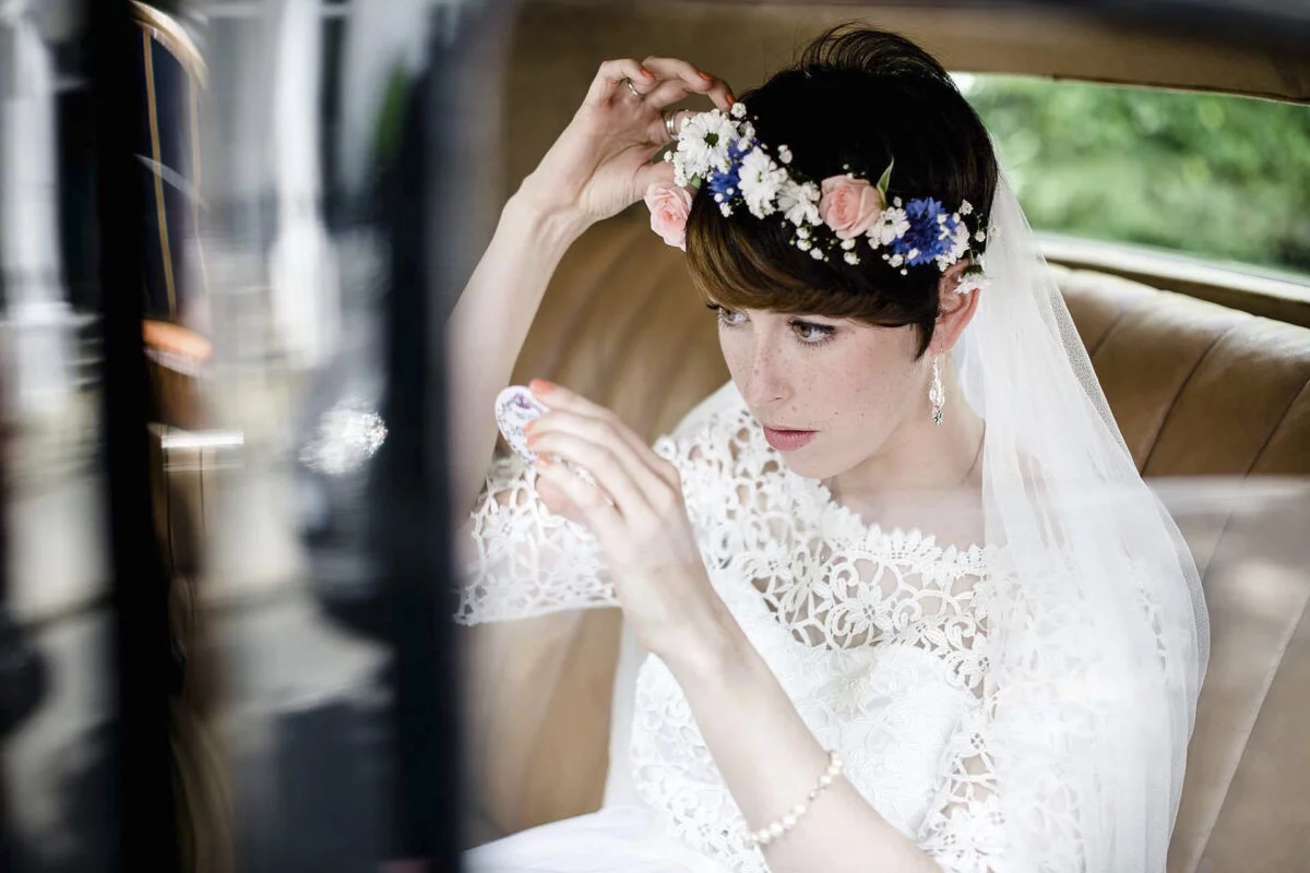 A bride is sitting in the back seat of a car.