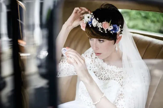 A bride is sitting in the back seat of a car.