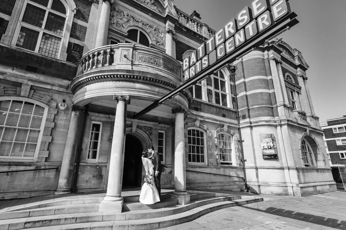 A black and white photo of a bride and groom standing in front of a building.