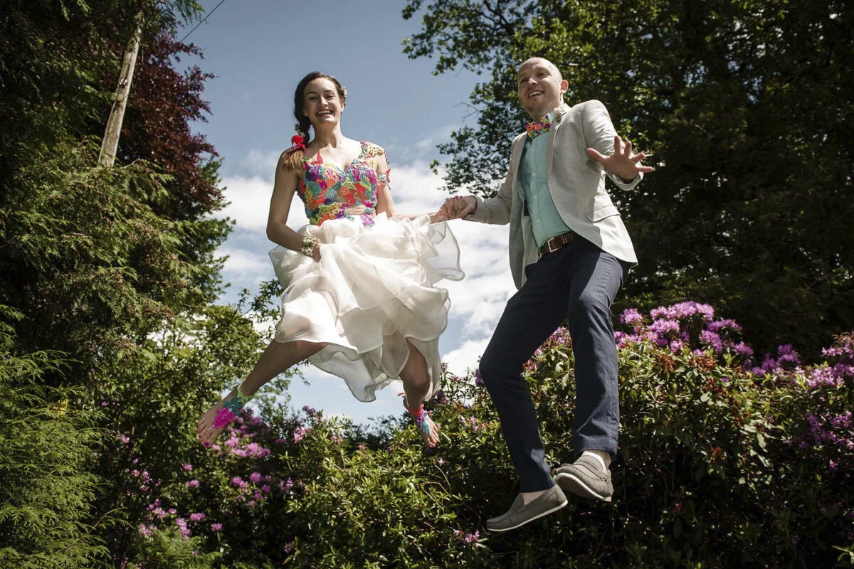 A bride and groom jumping in the air.