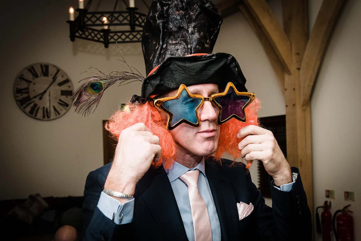 A man in a suit wearing a hat and glasses.