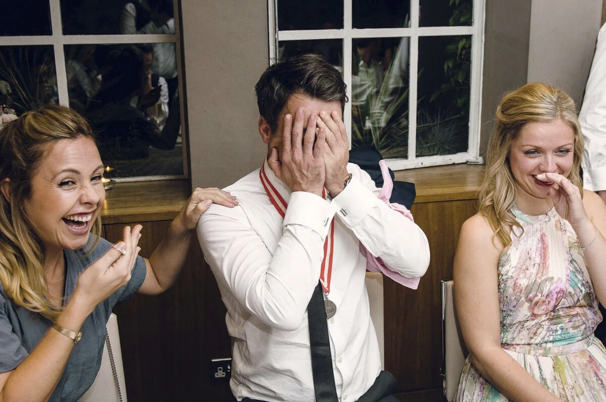 A group of people covering their faces at a wedding.
