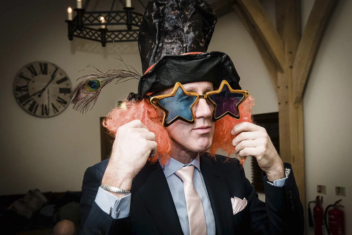 A man in a suit wearing a hat and glasses.