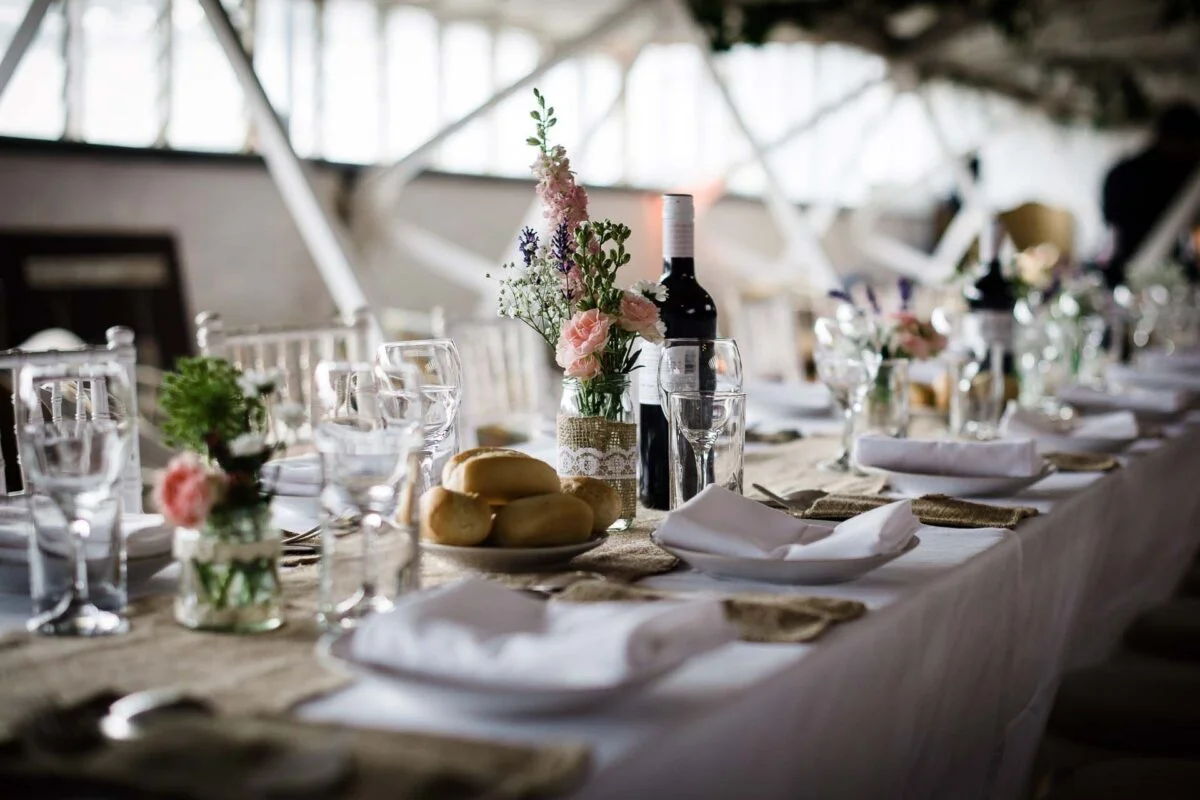 A long table set with wine glasses and flowers.