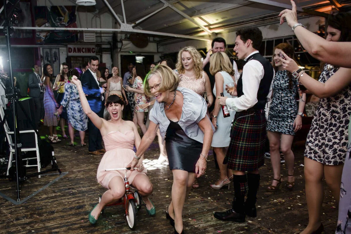 A woman riding a bike on the dance floor at a wedding.
