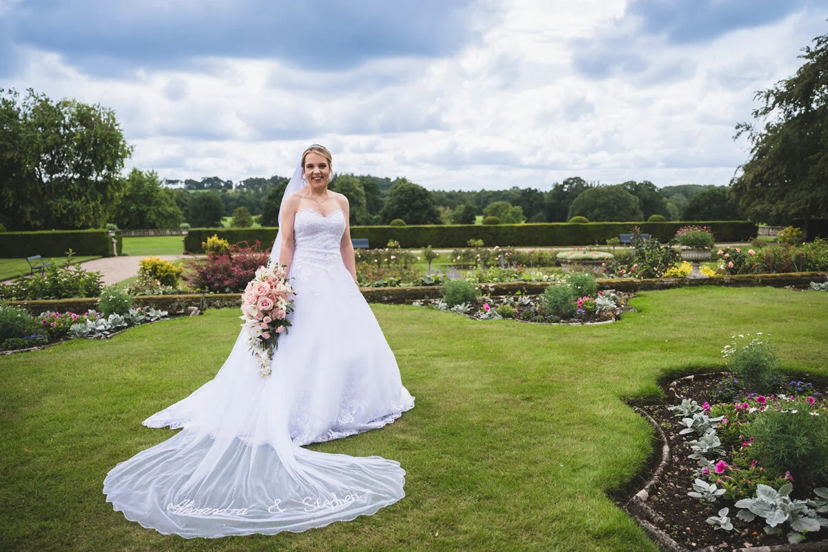A bride in a wedding dress standing in a garden.