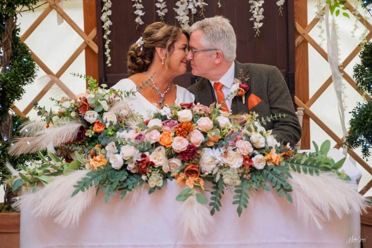 A bride and groom kissing in front of a yurt.