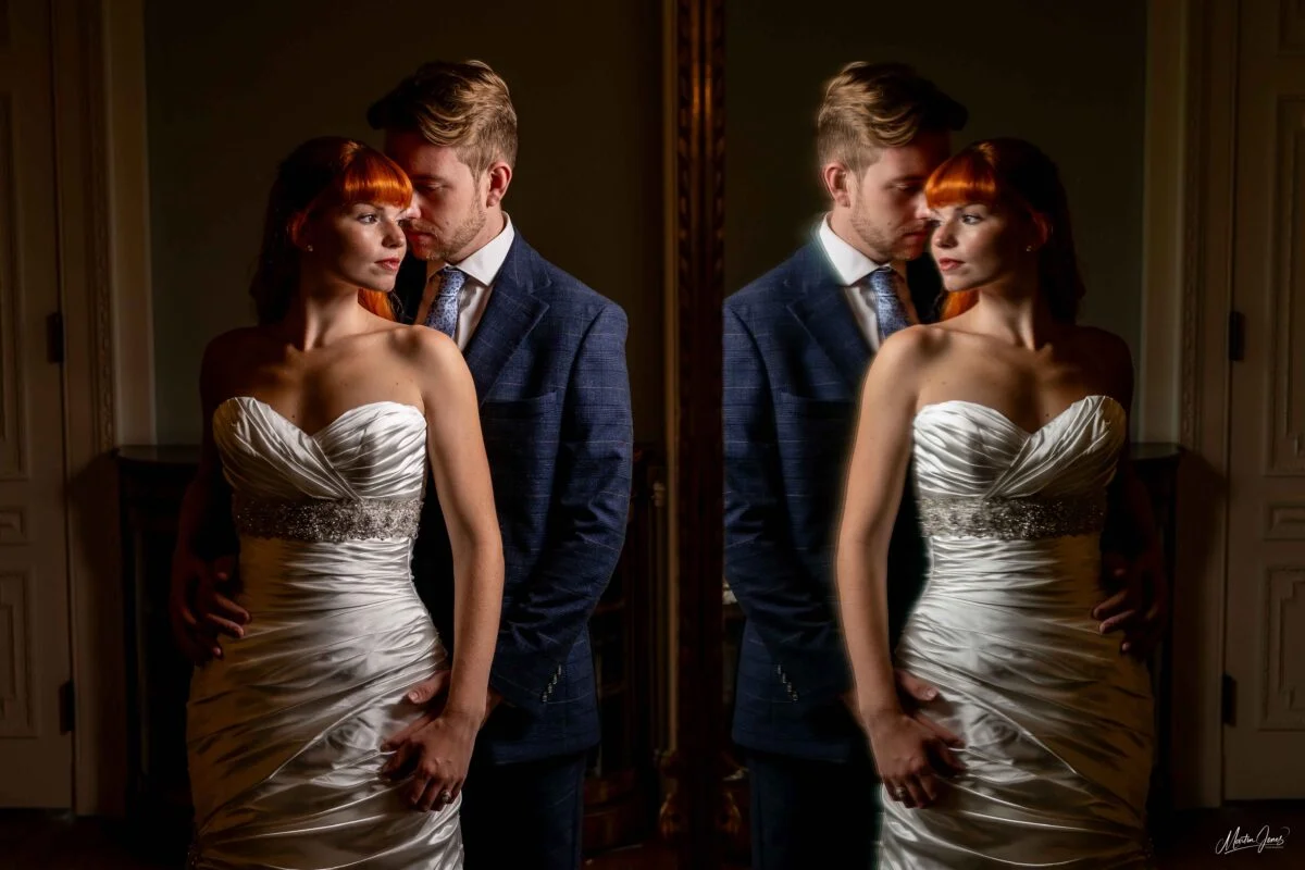 A bride and groom posing in front of a mirror.