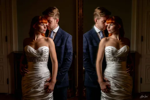 A bride and groom posing in front of a mirror.