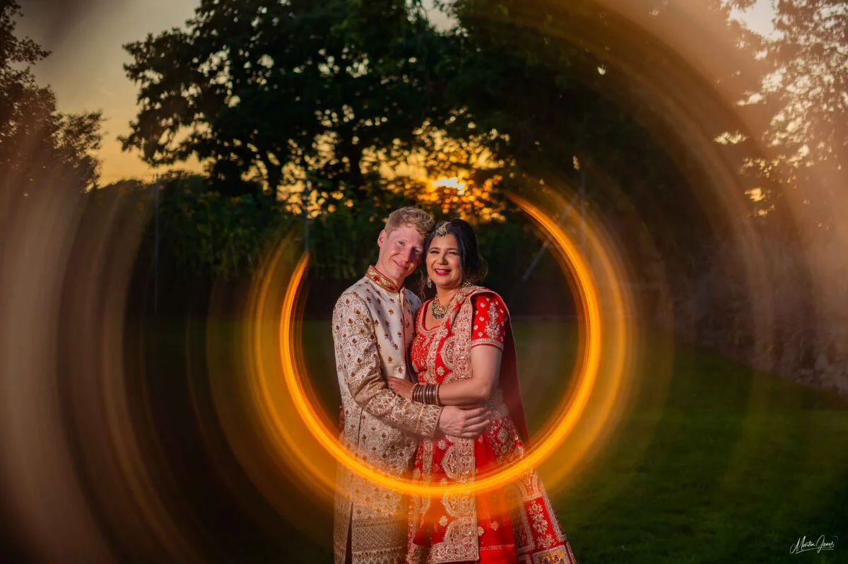 An indian couple posing in front of a circular light.