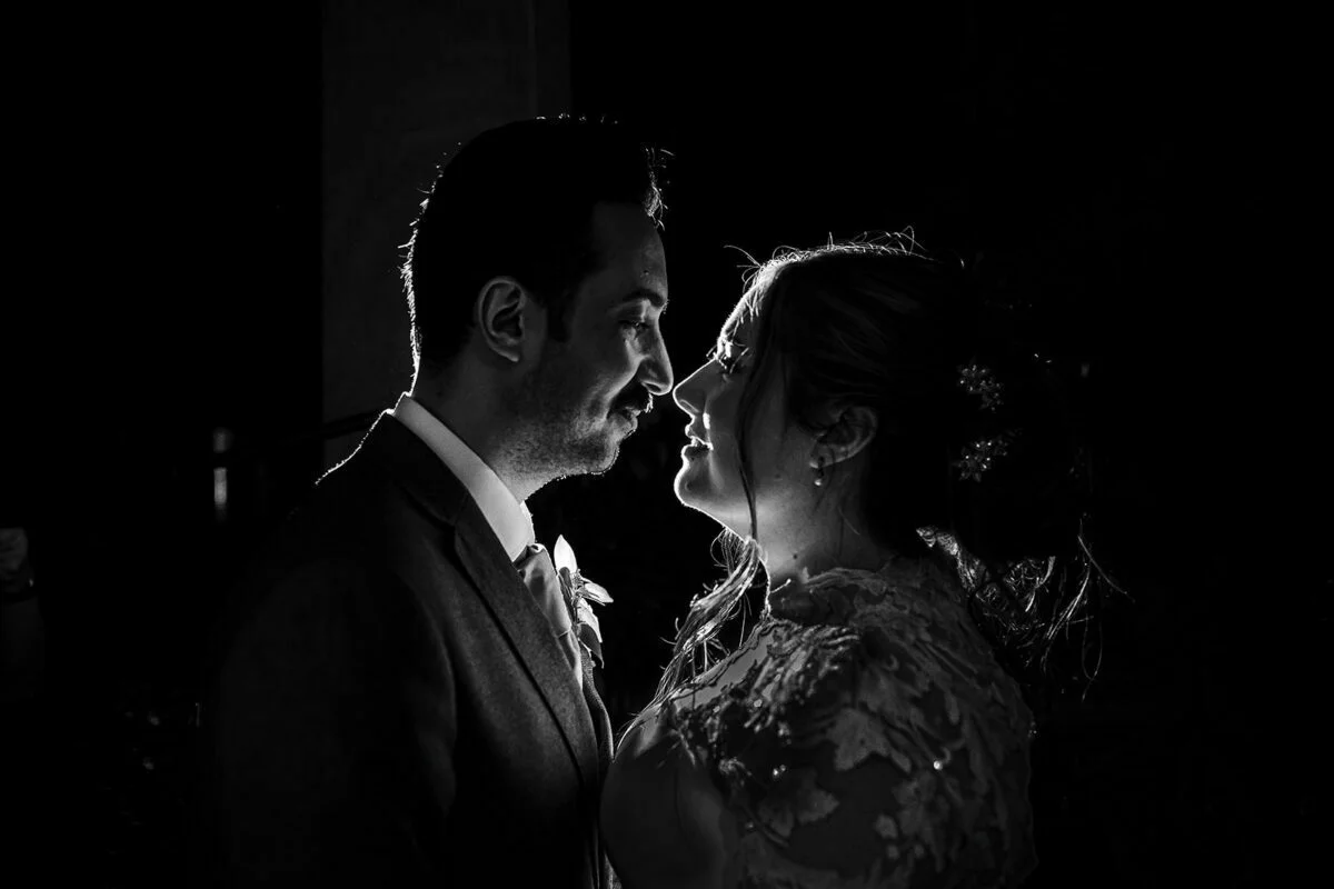 A black and white photo of a bride and groom sharing a kiss.