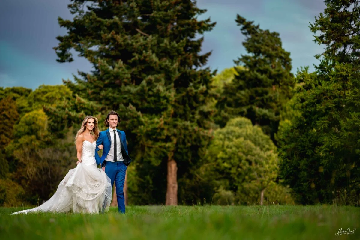A bride and groom standing in a grassy field.