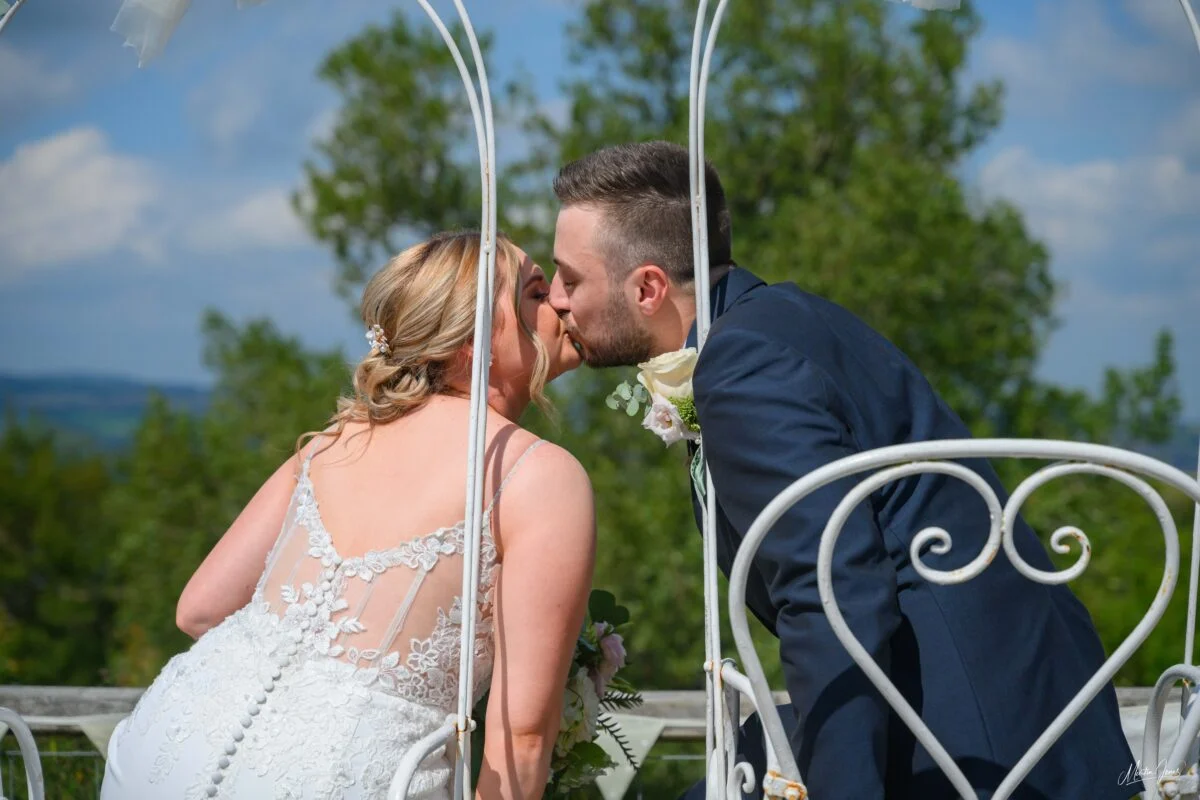 A bride and groom kissing in a white gazebo.