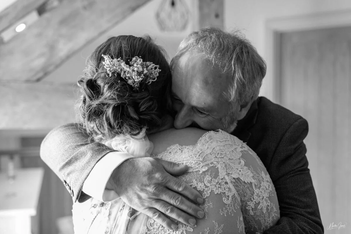 A black and white photo of a bride hugging her father.