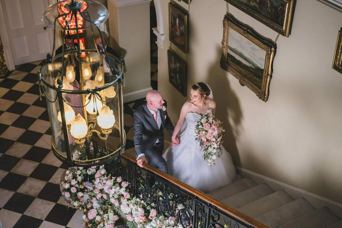 A bride and groom walking down a staircase.
