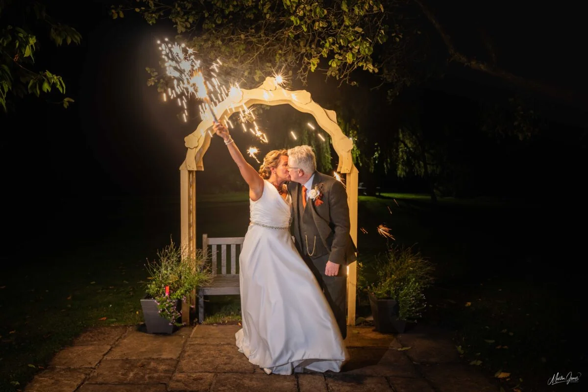A bride and groom with sparklers in their hands.